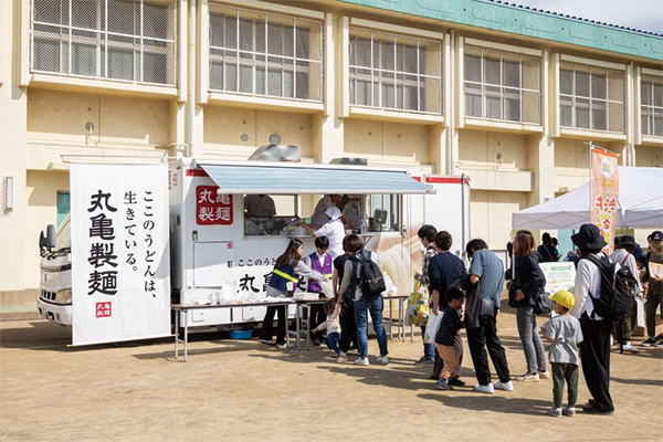 丸亀製麺のキッチンカーに列をつくって並ぶ人たちの様子