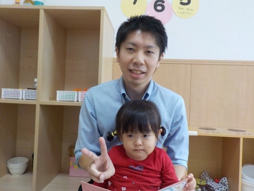子どもを抱えてピースする職員の写真