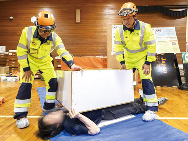 疑似的に家具の下敷きになり救出される体験をする参加者