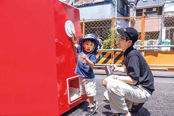 背伸びしてカプセルトイマシンのハンドルを回す子ども