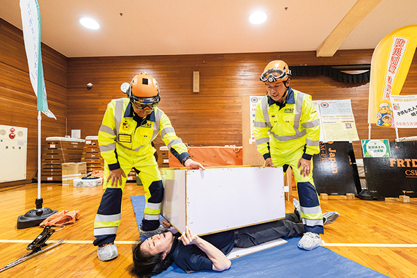 疑似的に家具の下敷きになり救出される体験をする参加者