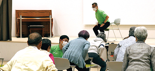 椅子から腰を浮かせてトレーニングをする参加者の様子