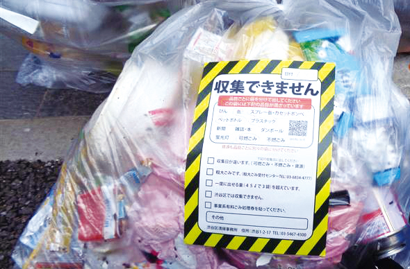 ごみ捨て場のごみ袋にごみ警告シールが貼られている様子