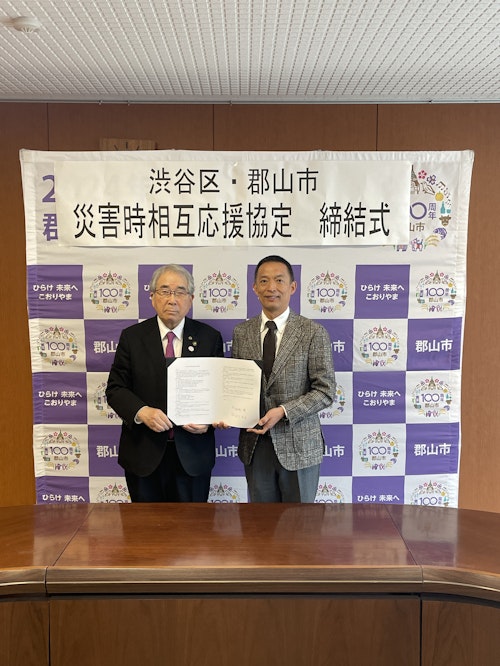 協定締結式にて郡山市長と渋谷区長が協定書を持っている写真