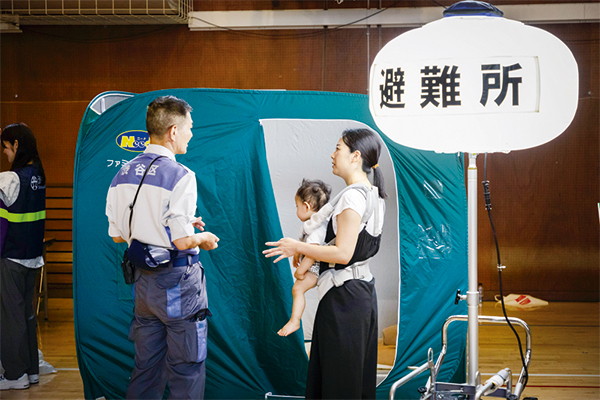 パーティションの前で説明を聴く参加者