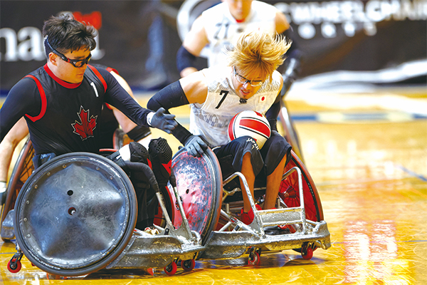 車いすラグビー競技中の様子、池崎選手と相手チームの選手の車いす同士がタックルしている