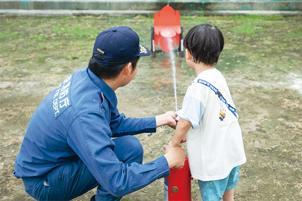 消防員と子どもが消火器を持って消化体験をしている様子