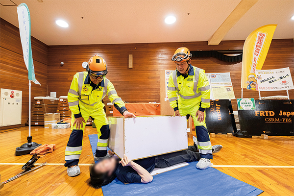 疑似的に家具の下敷きになり救出される体験をする参加者