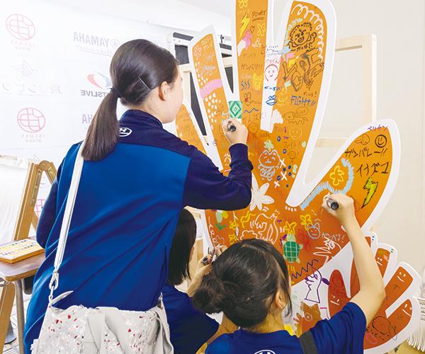 応援アートに文字や絵を書き込む中学生の皆さん
