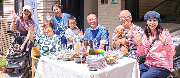 家の前のテーブルに座り和気あいあいとした様子のご近所さんたちと長谷部区長