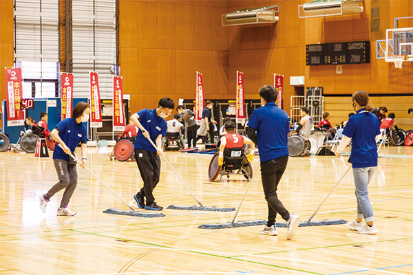 スポーツボランティアの人たちが屋内会場をモップがけしている様子