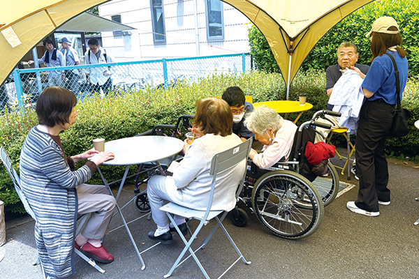 高齢者の皆さんが屋外のテーブルを囲んでいる様子